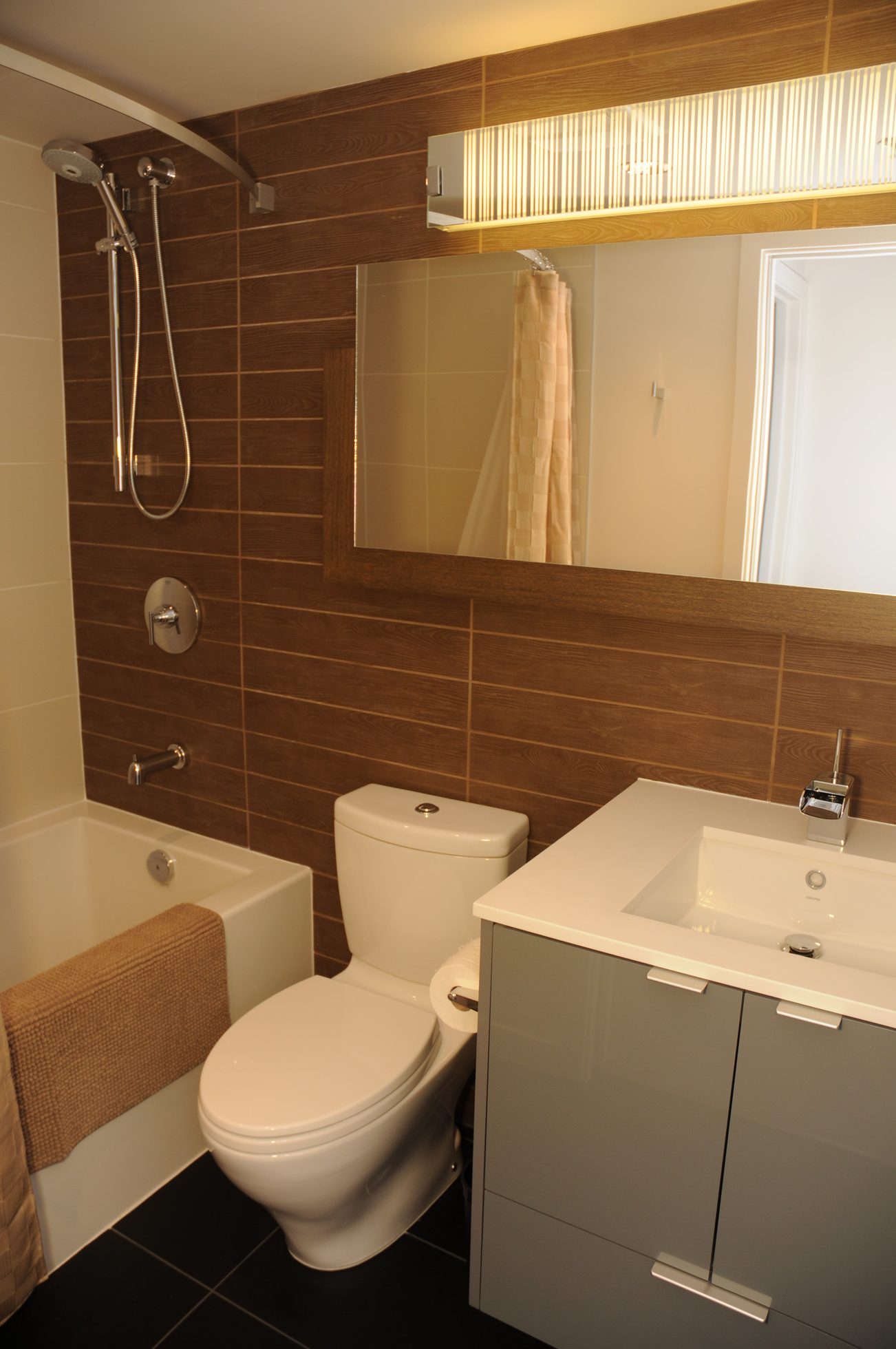 Furnished bathroom with modern sink, wooden wall tiles, and a bathtub with a shower. - 2201 - 161 West Georgia, Vancouver Downtown