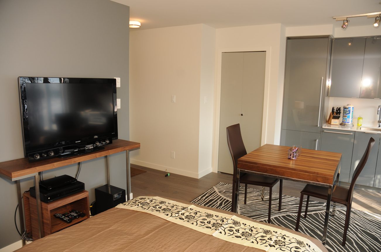 Bright living room with wooden furniture, kitchen counter, and city view. - 2206 - 161 West Georgia St, Vancouver Downtown