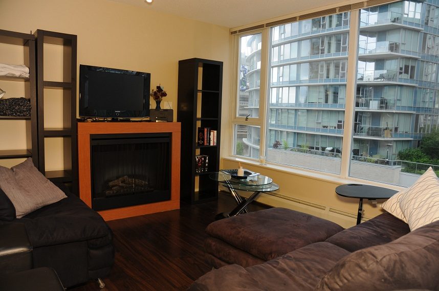 Living room with a fireplace, large windows, and city view. - 506 - 618 Abbott Street, Vancouver Downtown