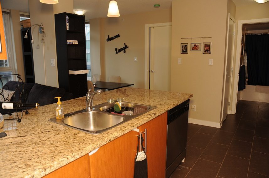 Bright kitchen with granite countertops and a modern sink, featuring a "dream laugh" wall decor. - 506 - 618 Abbott Street, Vancouver Downtown