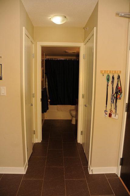 Bright hallway leading to a cozy bathroom with dark tiles and a black shower curtain. - 506 - 618 Abbott Street, Vancouver Downtown