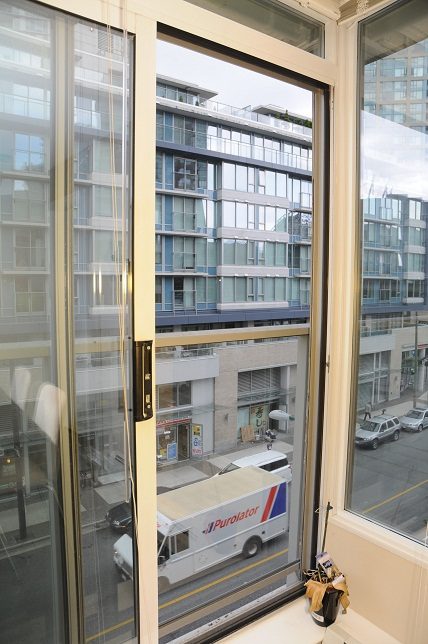 Bright living room with large windows offering a city view and modern furnishings. - 506 - 618 Abbott Street, Vancouver Downtown