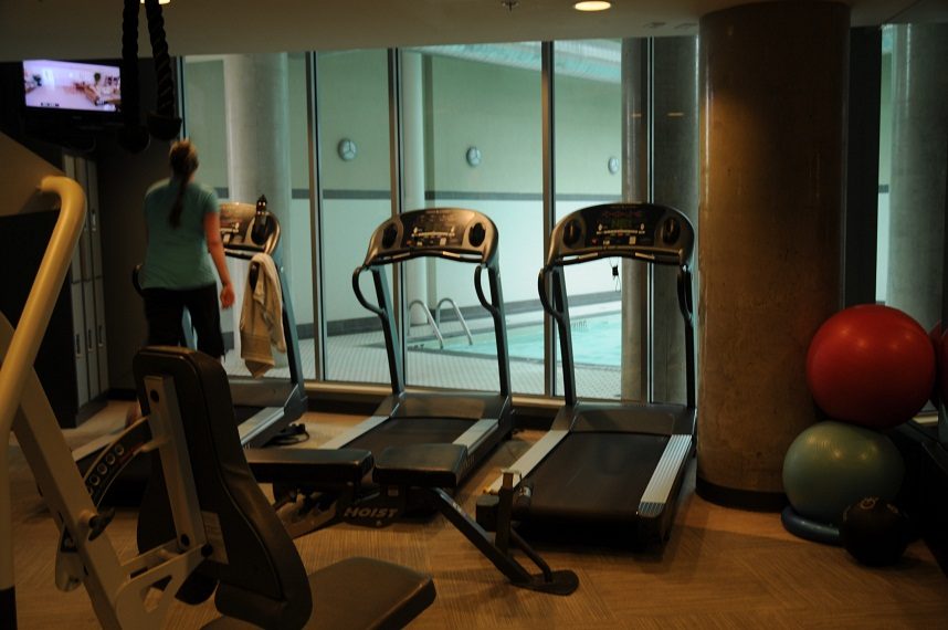 Bright fitness room with treadmills and exercise equipment, overlooking a pool area. - 506 - 618 Abbott Street, Vancouver Downtown