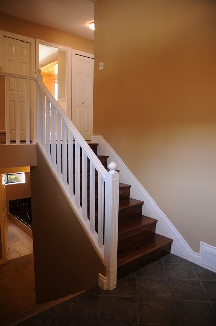 Staircase leading to upper level with white railings and dark wood steps. - 5591 Huckleberry Place, North Vancouver
