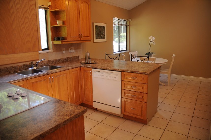 Bright kitchen with granite countertops, wooden cabinets, and a tiled floor. - 5591 Huckleberry Place, North Vancouver