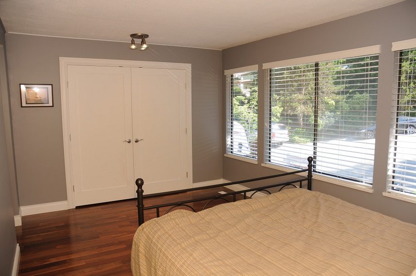 Bright bedroom with hardwood floors, large windows, and a neatly made bed. - 5591 Huckleberry Place, North Vancouver