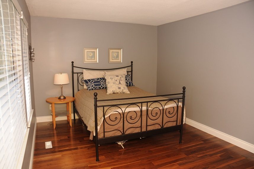 Furnished bedroom with hardwood floors and a metal bed frame. - 5591 Huckleberry Place, North Vancouver