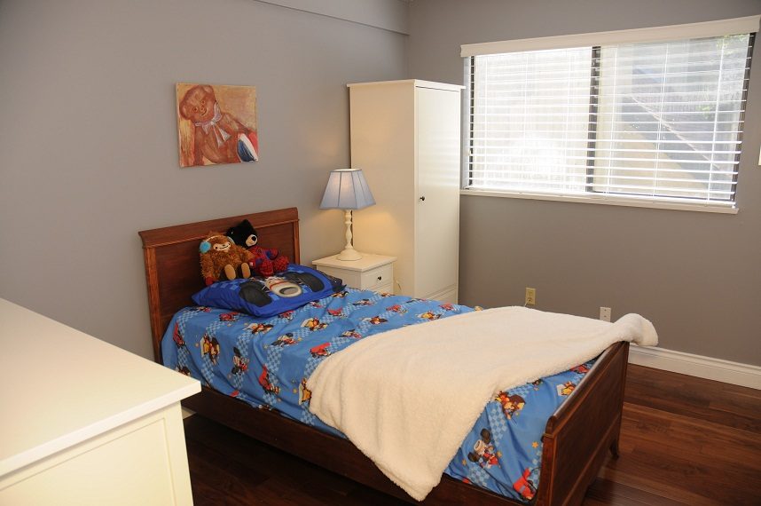 Bright bedroom with wooden floors, blue Mickey Mouse bedspread, and a white dresser. - 5591 Huckleberry Place, North Vancouver