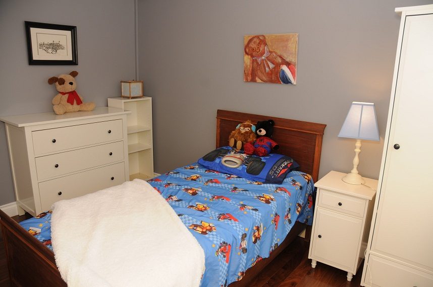 Bright bedroom with wooden bed, superhero-themed bedding, and plush toys. - 5591 Huckleberry Place, North Vancouver