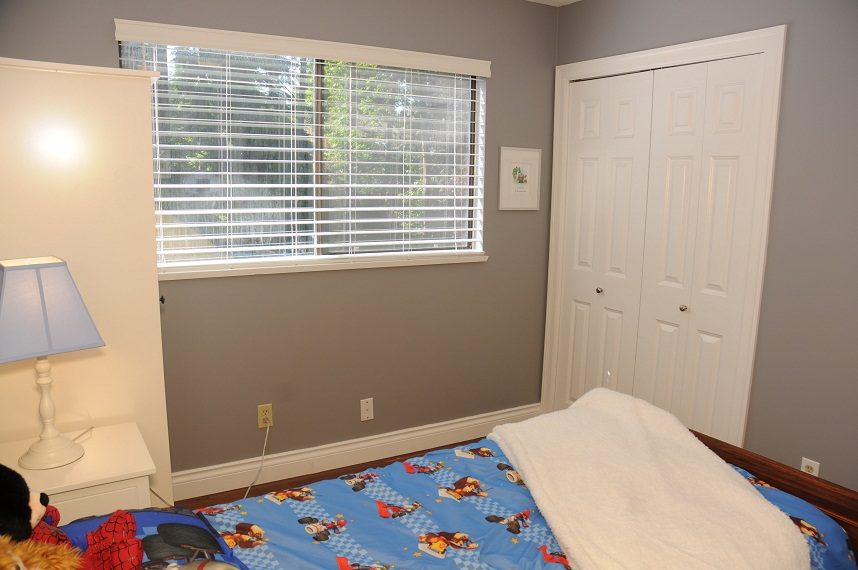 Bright bedroom with blue superhero-themed bedspread, white closet door, and window with blinds. - 5591 Huckleberry Place, North Vancouver