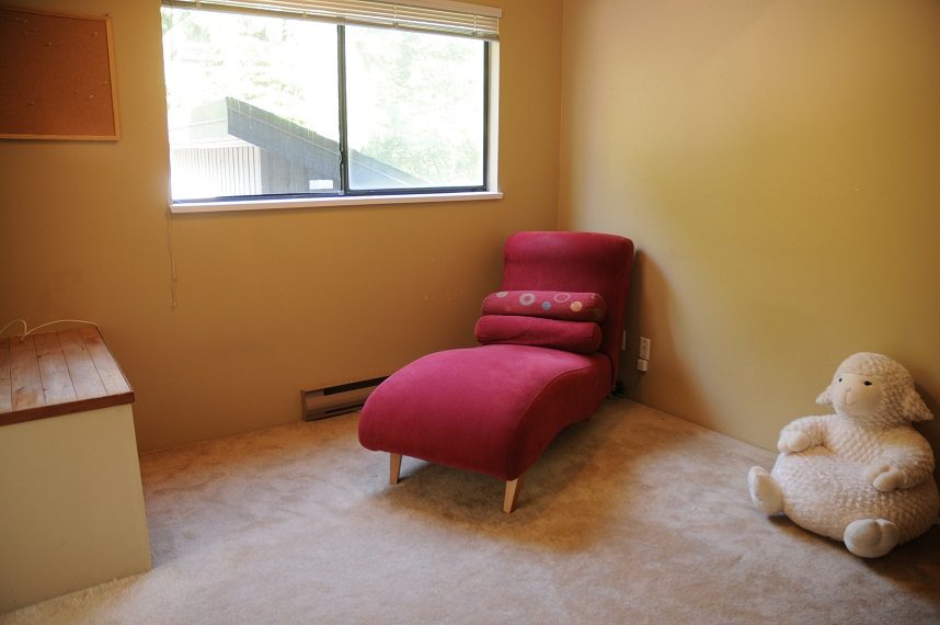 Bright den with a red chaise lounge and plush sheep, light carpet, and a window view. - 5591 Huckleberry Place, North Vancouver