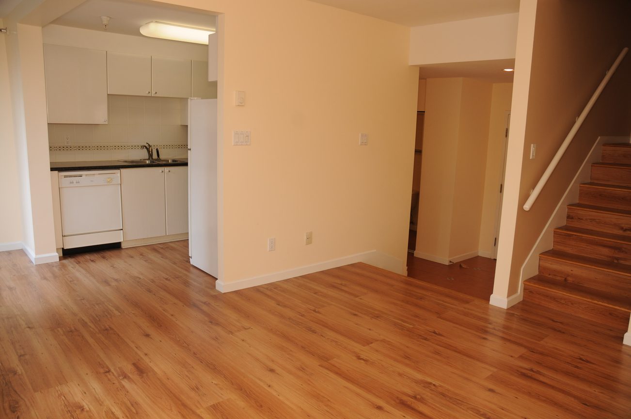 Open-concept living area with hardwood floors and a view of the kitchen. - 211 - 1166 Melville St, Vancouver Downtown