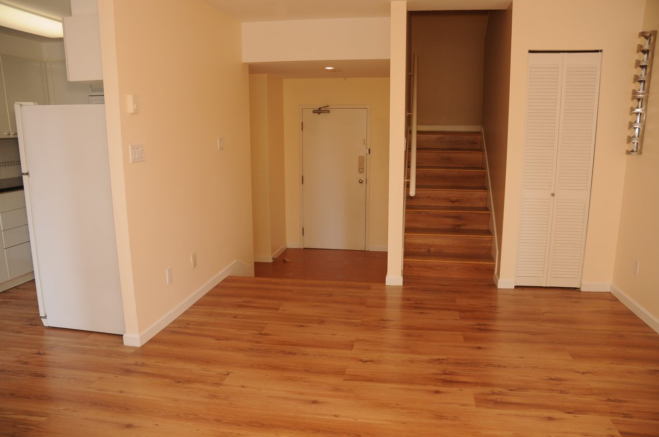 Bright living room with hardwood floors and a view of the staircase leading to the upper level. - 211 - 1166 Melville St, Vancouver Downtown