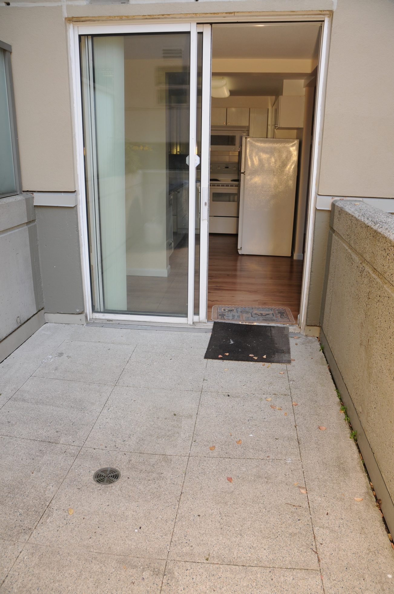 Bright kitchen with hardwood floors and a sliding glass door leading to a patio. - 211 - 1166 Melville St, Vancouver Downtown