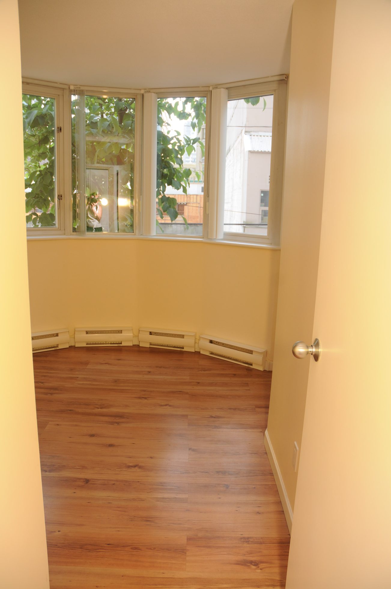 Bright sunlit corner room with hardwood floors and bay window view. - 211 - 1166 Melville St, Vancouver Downtown