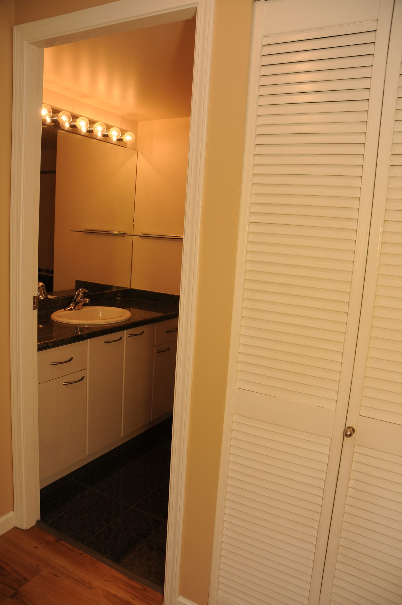 Furnished bathroom with black countertops and white louvered closet doors. - 211 - 1166 Melville St, Vancouver Downtown