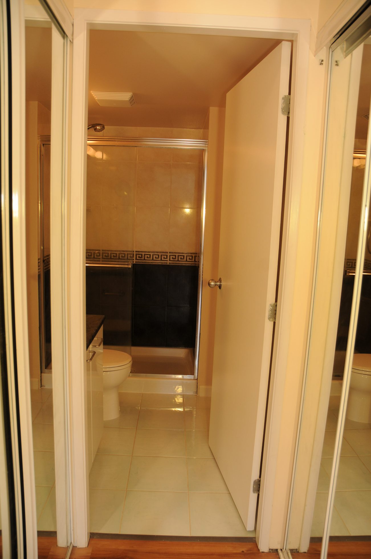Bright bathroom with white door, black and gold tiled shower, and white countertop. - 211 - 1166 Melville St, Vancouver Downtown