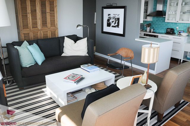 Furnished living room with modern furniture, hardwood floors, and a kitchen in the background. - 1802- 2055 Pendrell, Vancouver Downtown