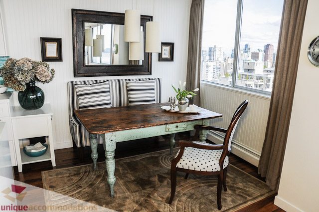 Furnished dining area with wooden table, striped bench, city view, and modern decor. - 1802- 2055 Pendrell, Vancouver Downtown