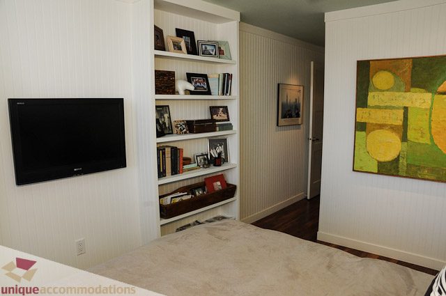 Bright living room with white walls, built-in shelves, and a large abstract painting. - 1802- 2055 Pendrell, Vancouver Downtown