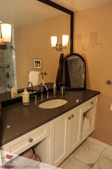 Bathroom with dark countertop, white cabinets, and wall-mounted lights. - 1802- 2055 Pendrell, Vancouver Downtown