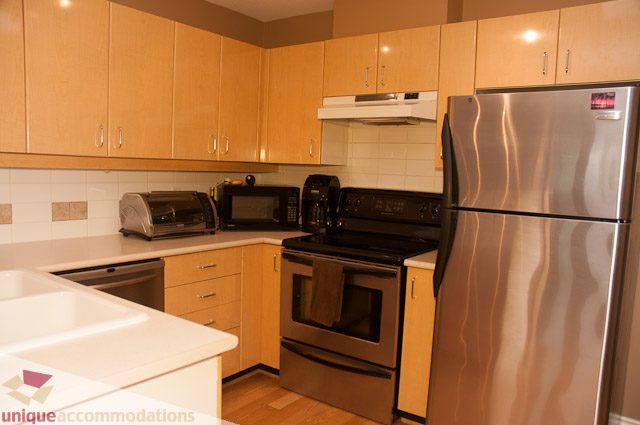 Bright kitchen with light wood cabinets, stainless steel appliances, and granite countertops. - 402- 2680 West 4th Ave PH2, Vancouver West Side