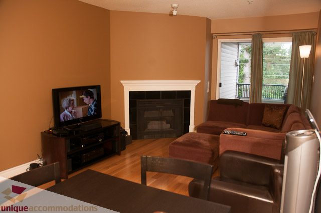 Living room with a fireplace, hardwood floors, and a view of the balcony. - 402- 2680 West 4th Ave PH2, Vancouver West Side