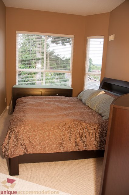 Bright bedroom with a cozy bed, patterned bedding, and a view of greenery outside. - 402- 2680 West 4th Ave PH2, Vancouver West Side