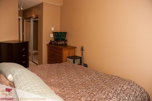 Furnished 1-bedroom with wooden dresser and patterned bedding. - 402- 2680 West 4th Ave PH2, Vancouver West Side