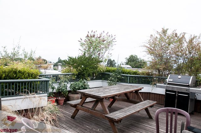 Furnished patio with wooden furniture, greenery, and city view. - 402- 2680 West 4th Ave PH2, Vancouver West Side