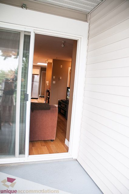 Furnished living room with hardwood floors and sliding glass door leading to a balcony. - 402- 2680 West 4th Ave PH2, Vancouver West Side