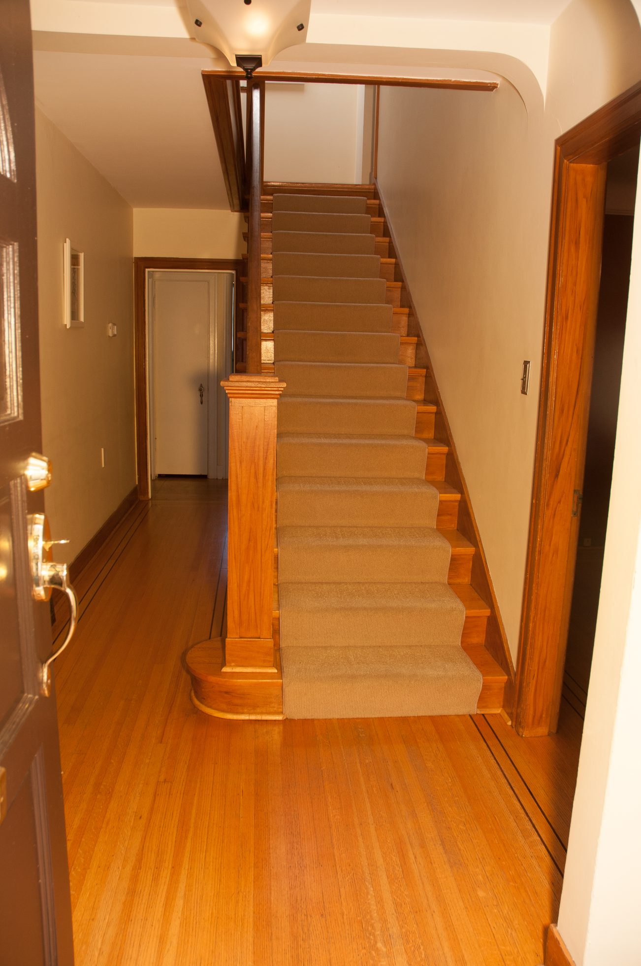 Bright hallway leading to a carpeted staircase with wooden railings and hardwood floors. - 3249 West 36th Ave, Vancouver West Side