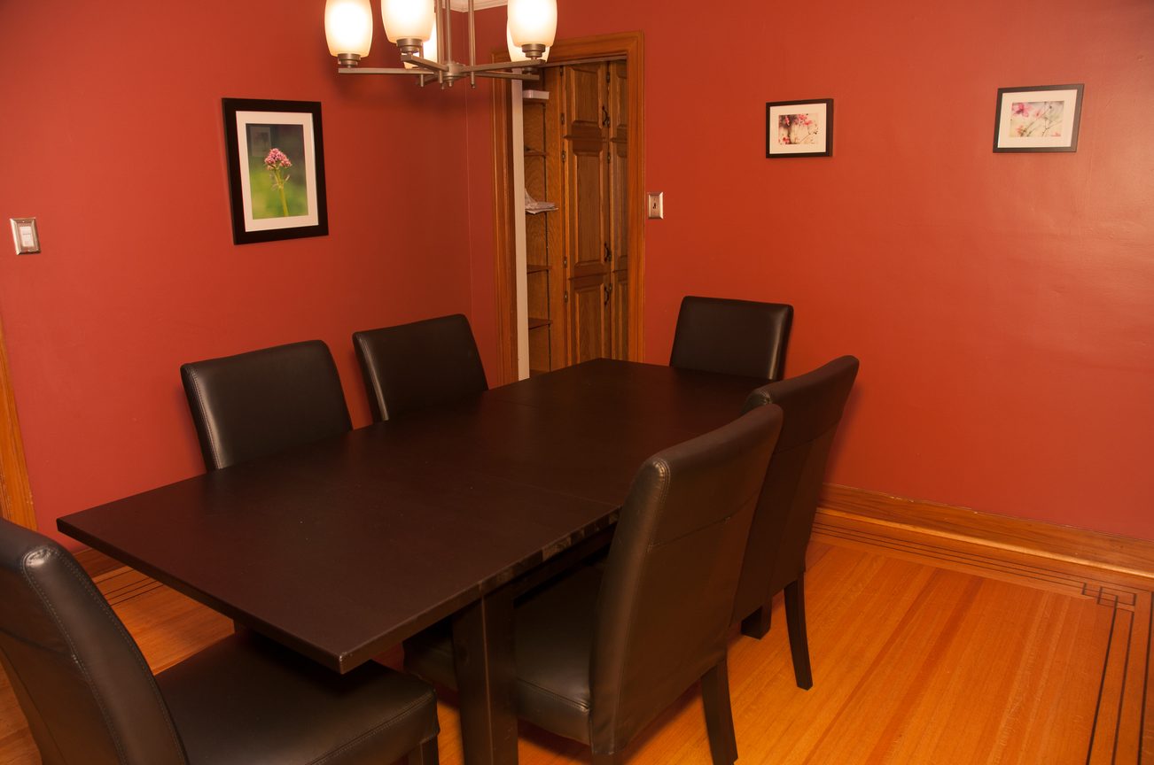 Dining room with dark wood table, black leather chairs, and red walls. - 3249 West 36th Ave, Vancouver West Side