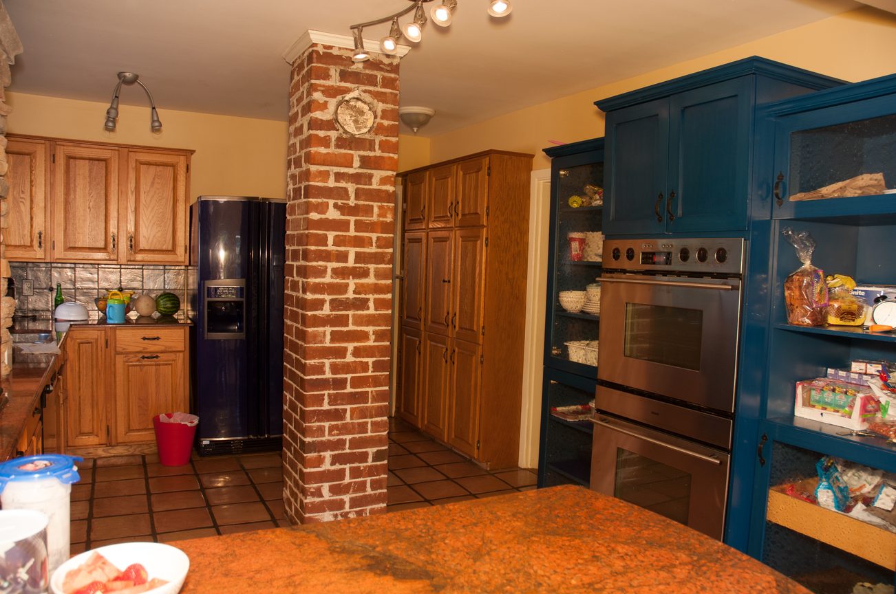 Bright kitchen with blue cabinets, brick accent wall, and tiled floor. - 3249 West 36th Ave, Vancouver West Side