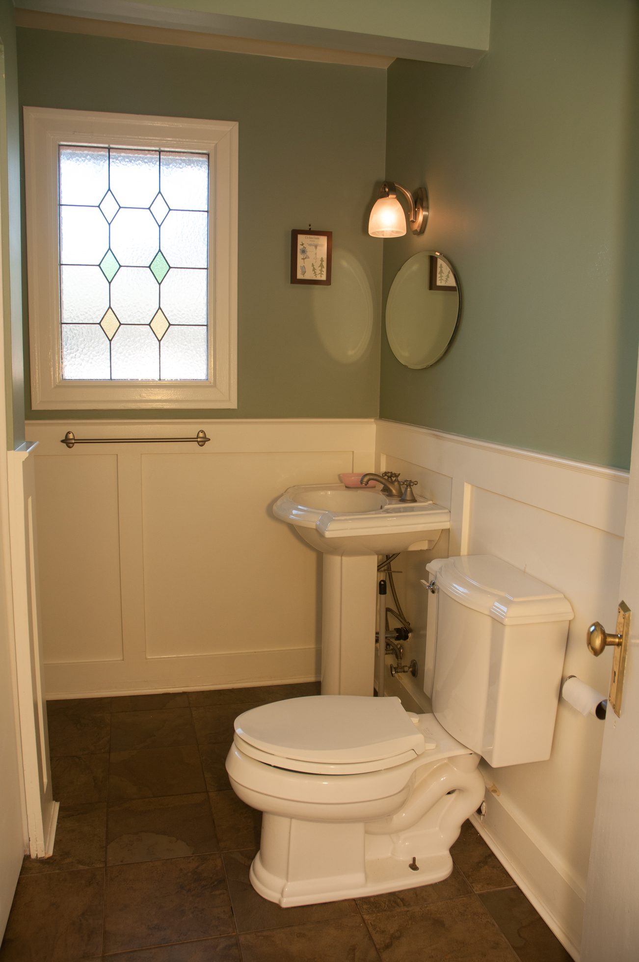 Bright bathroom with pedestal sink, stained glass window, and white wainscoting. - 3249 West 36th Ave, Vancouver West Side