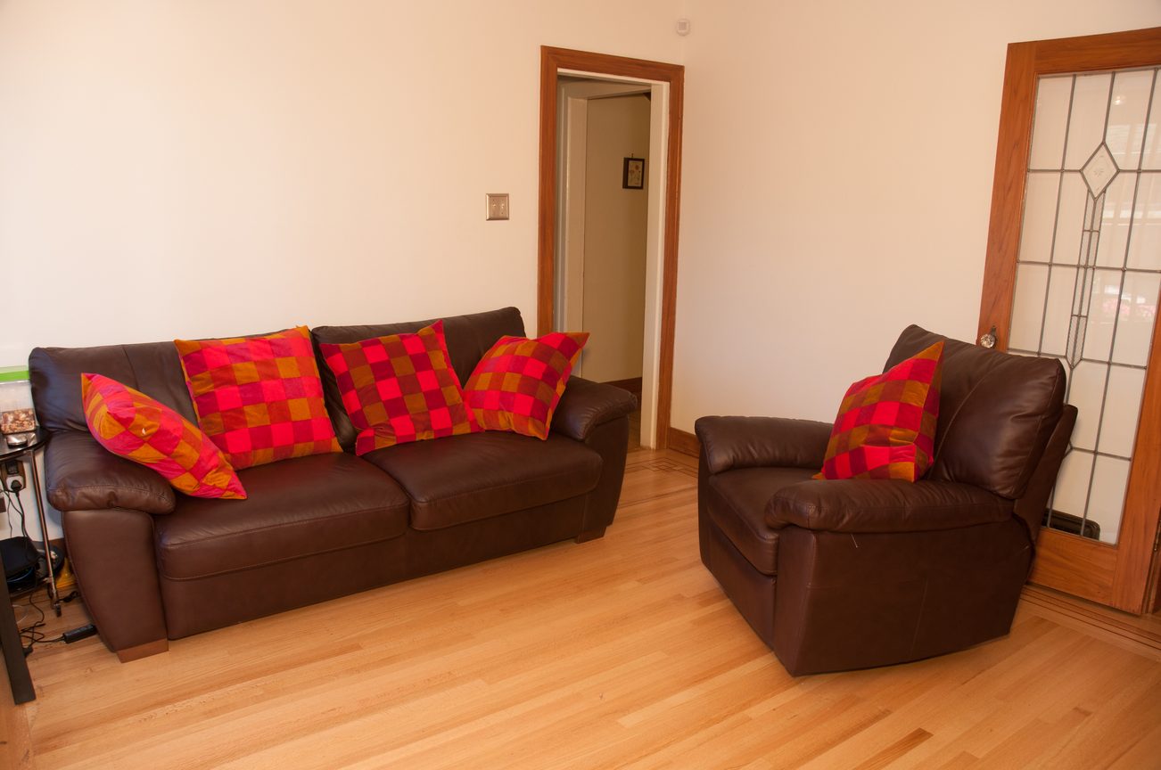 Furnished living room with brown leather furniture and checkered cushions, hardwood floors. - 3249 West 36th Ave, Vancouver West Side