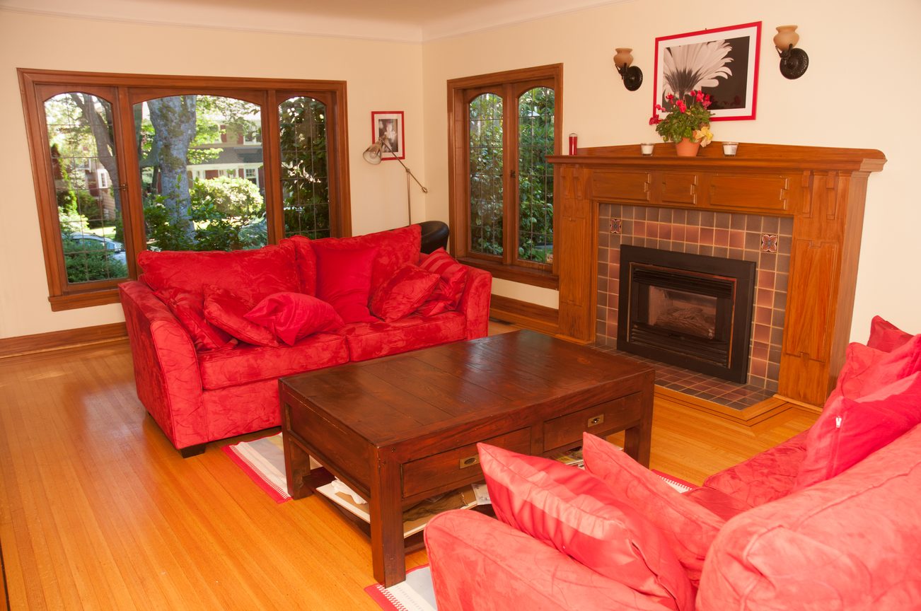 Furnished living room with red couches, wooden coffee table, and fireplace. - 3249 West 36th Ave, Vancouver West Side