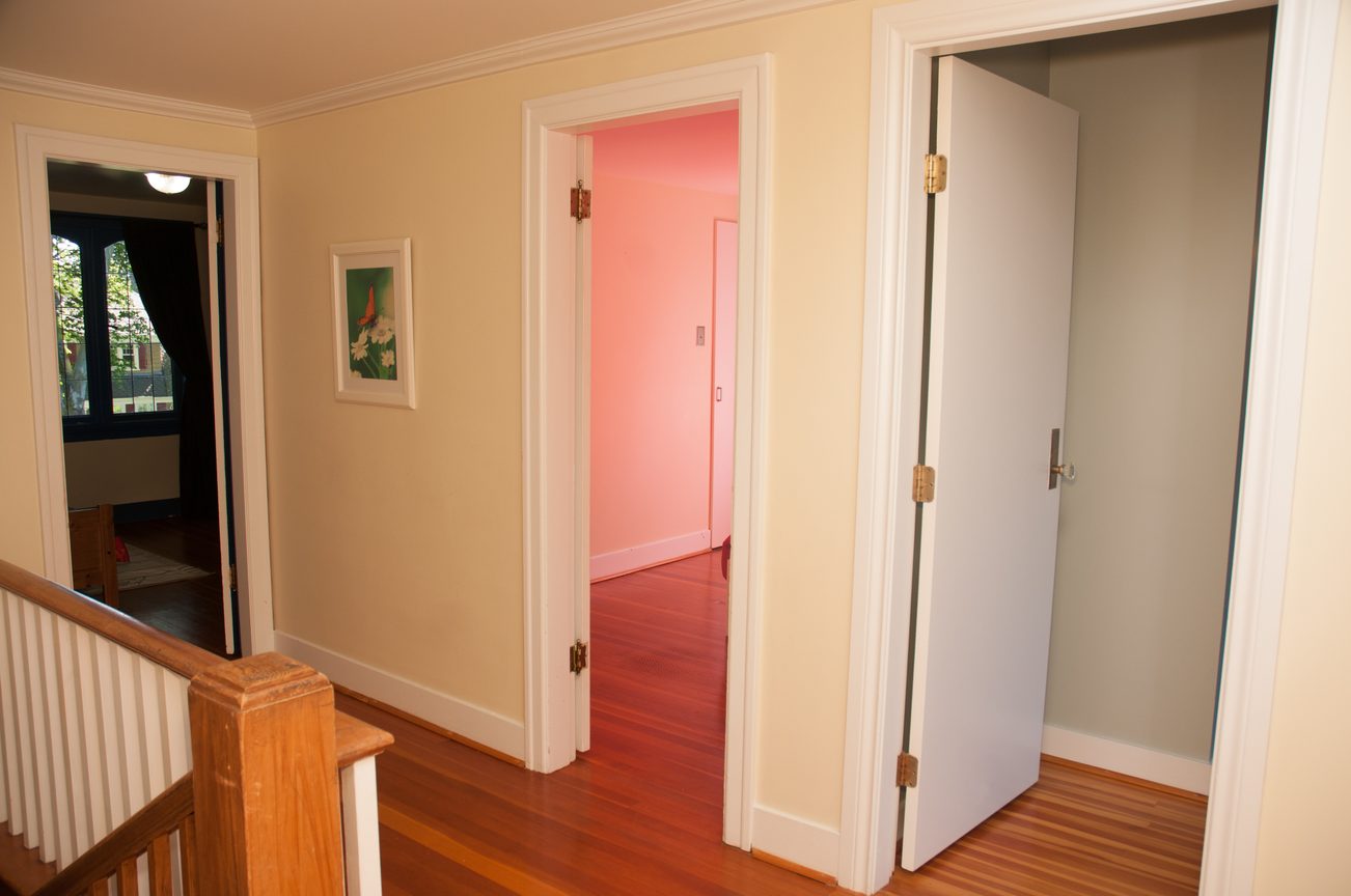 Bright hallway with hardwood floors and a pink door leading to another room. - 3249 West 36th Ave, Vancouver West Side