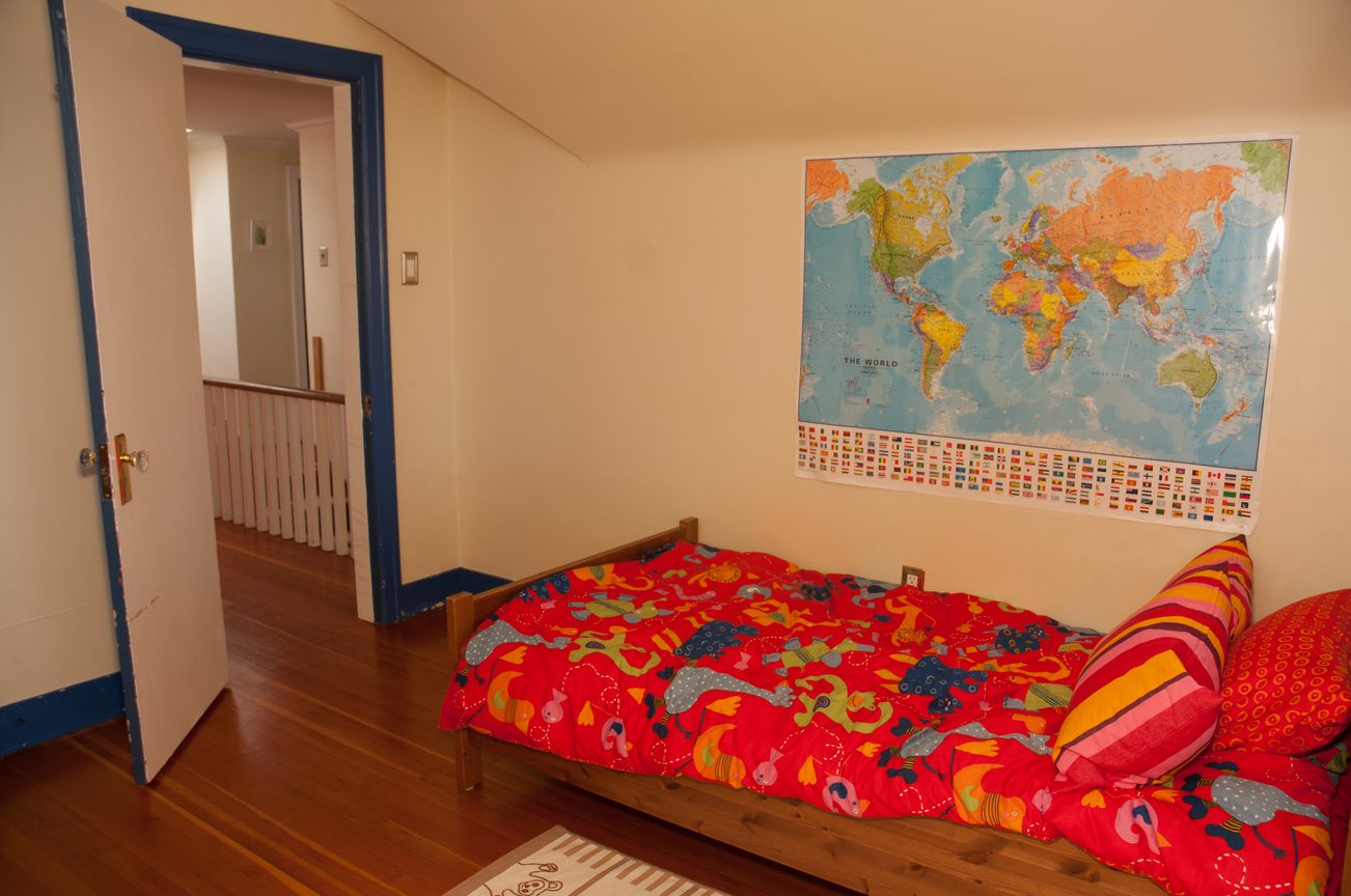 Bright bedroom with hardwood floors, colorful bedding, and world map on the wall. - 3249 West 36th Ave, Vancouver West Side