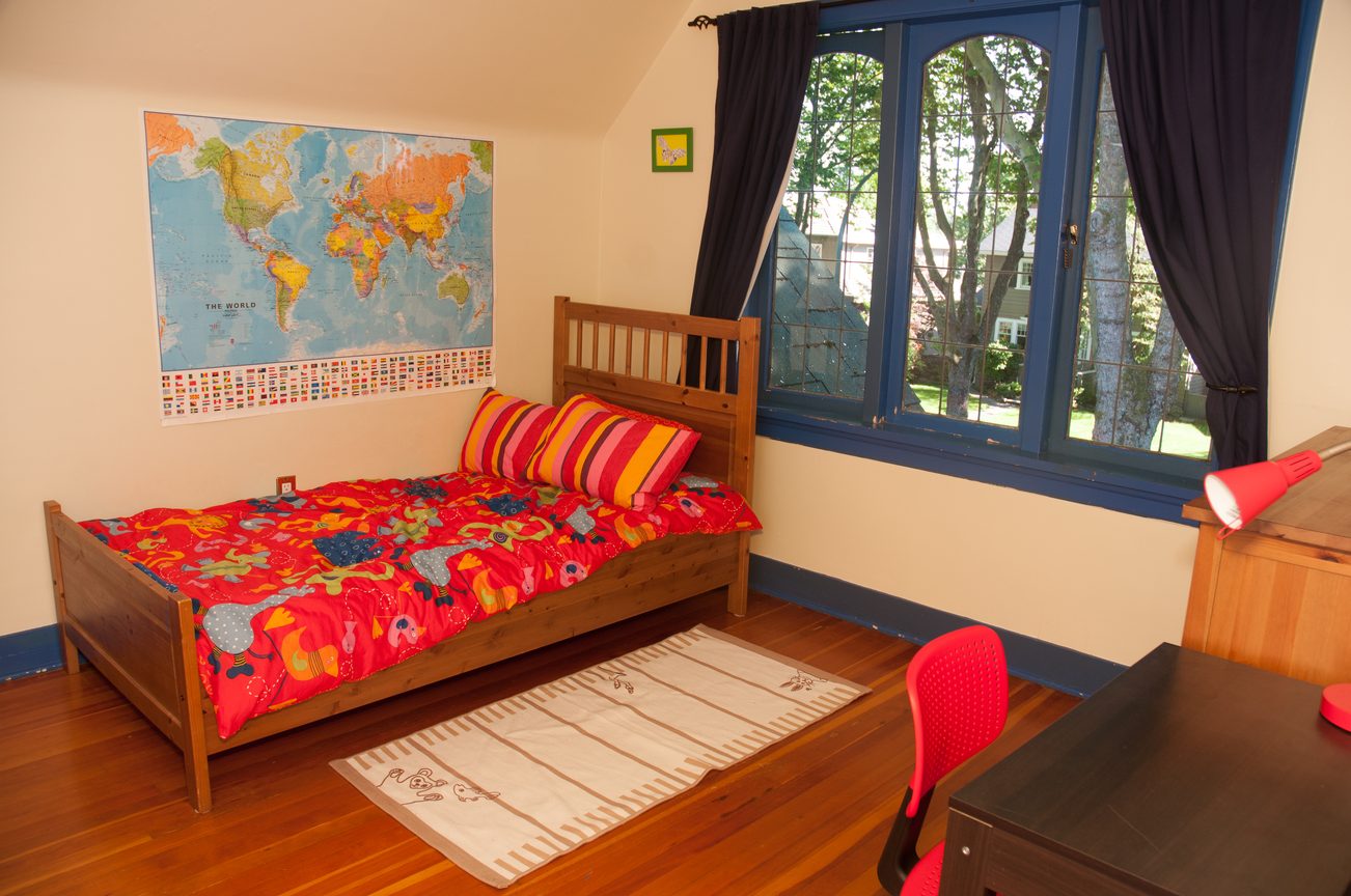 Bright bedroom with hardwood floors, colorful bedding, and a world map on the wall. - 3249 West 36th Ave, Vancouver West Side