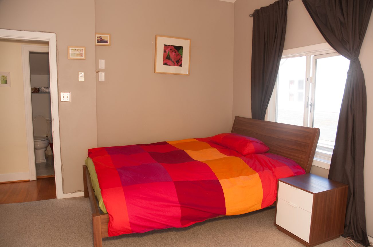 Bright bedroom with colorful bedding and large window, natural light streaming in. - 3249 West 36th Ave, Vancouver West Side