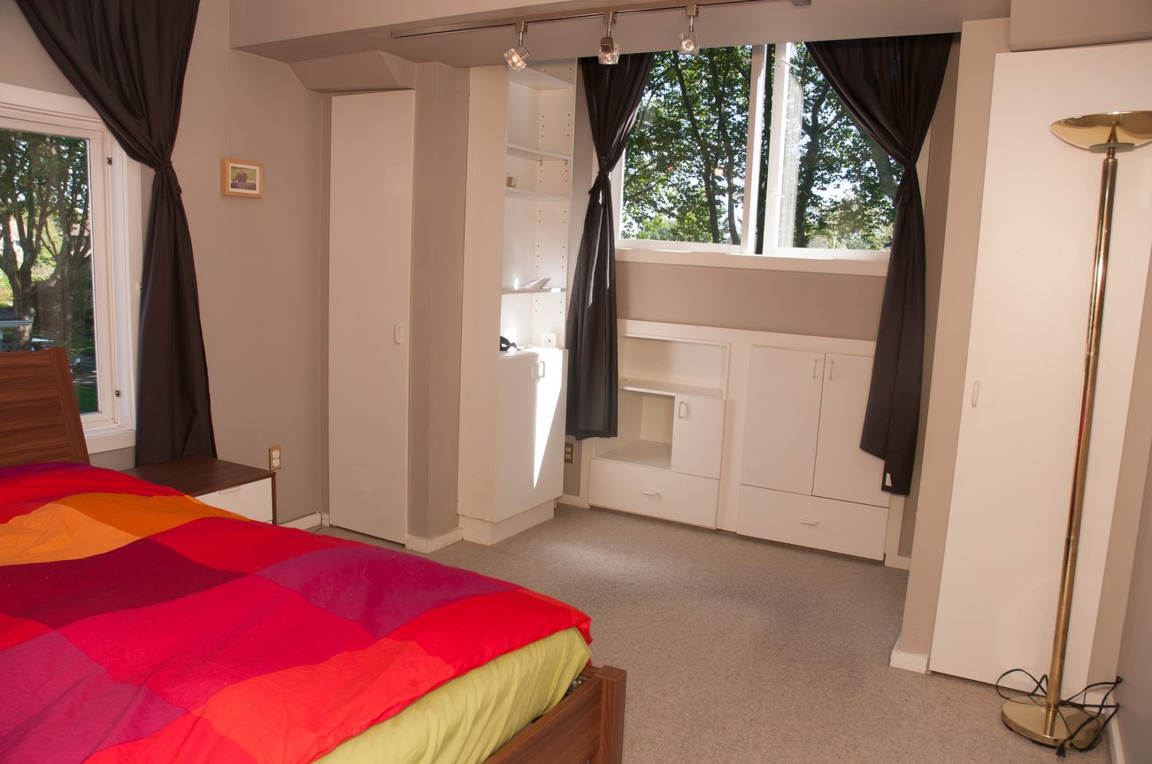Bright bedroom with colorful bedding and built-in storage, large windows with curtains. - 3249 West 36th Ave, Vancouver West Side