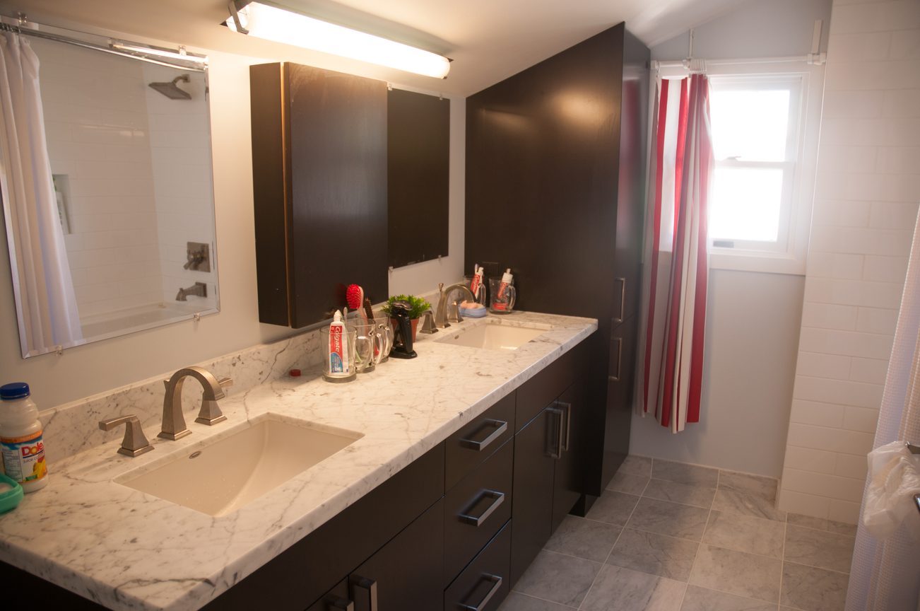 Bathroom with double sinks, marble countertops, and dark cabinets. - 3249 West 36th Ave, Vancouver West Side