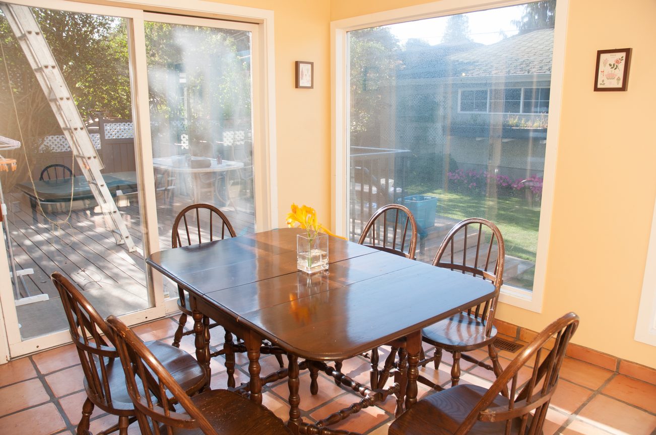 Bright dining area with wooden table and chairs, leading to a deck with sliding glass doors. - 3249 West 36th Ave, Vancouver West Side