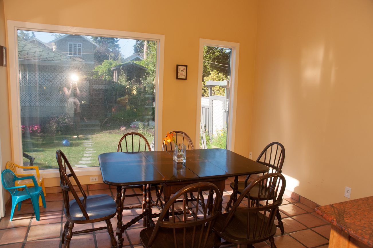 Bright dining area with wooden table, colorful chairs, and a view of the backyard. - 3249 West 36th Ave, Vancouver West Side