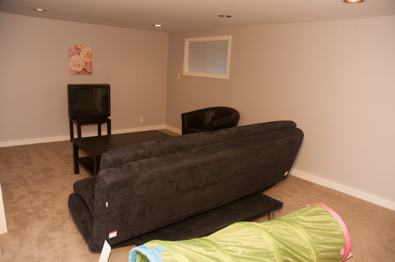 Living room with dark furniture and a small TV setup. - 3249 West 36th Ave, Vancouver West Side