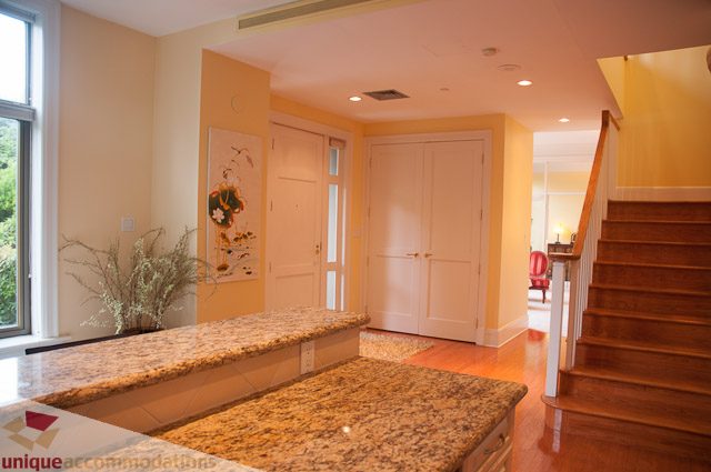 Bright kitchen with granite countertops and wooden staircase leading to upper level. - 103-2288 Bellevue Ave, West Vancouver