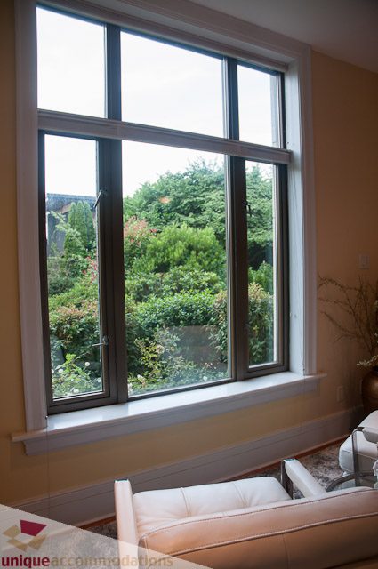 Bright living room with large windows overlooking greenery, modern furnishings. - 103-2288 Bellevue Ave, West Vancouver