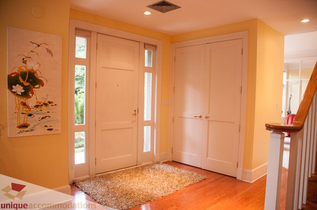 Bright entryway with hardwood floors and a white door, leading to a cozy living area. - 103-2288 Bellevue Ave, West Vancouver