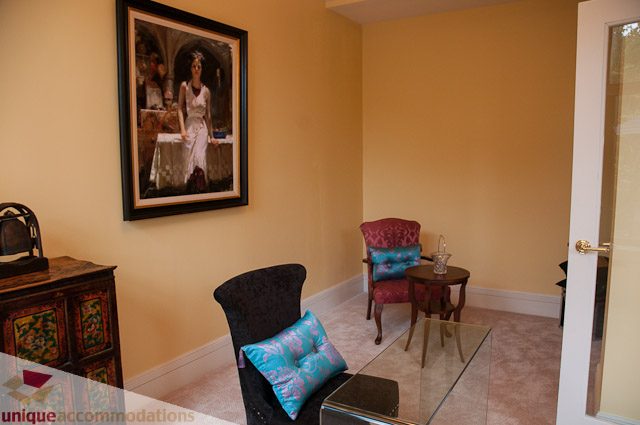 Furnished living room with vibrant artwork and patterned cushions. - 103-2288 Bellevue Ave, West Vancouver